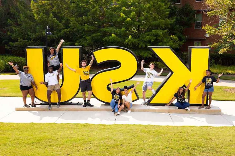 Group of 正规博彩十大网站排名 students taking a picture by the 正规博彩十大网站排名 sign.